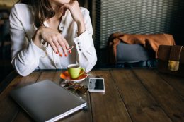 Woman with polysubstance abuse disorder sitting at a table while drinking coffee and smoking a cigarette.
