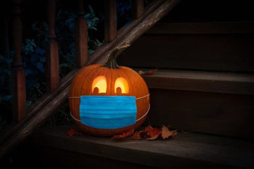 Jack-o-lantern with a mask sitting on a porch.