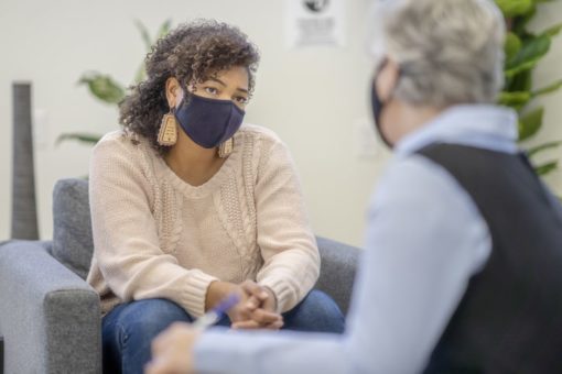 Patient and therapist sitting together both with masks on.