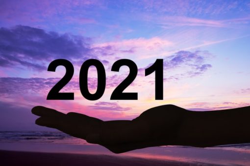 Hand offering 2021 numbers against a beach sunset background