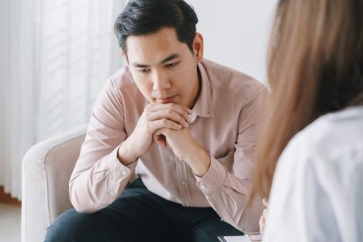 Male patient with woman therapist receiving psychotherapy in a clinic.
