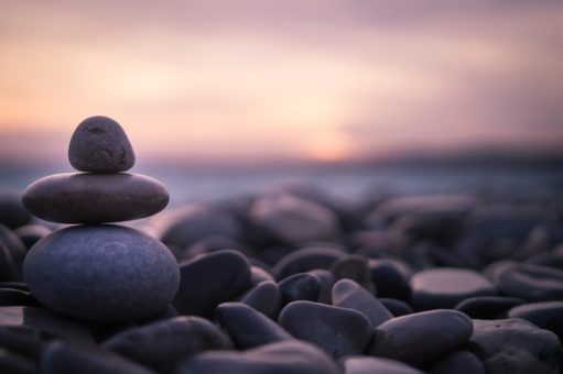 Stack of pebbles on beach during sunset.