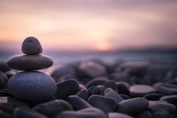 Stack of pebbles on beach during sunset.