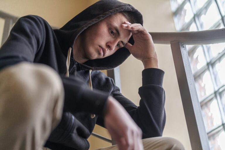 Teenager looking down with his hand on his forehead, reflecting oppositional defiant disorder symptoms such as frustration and irritability.